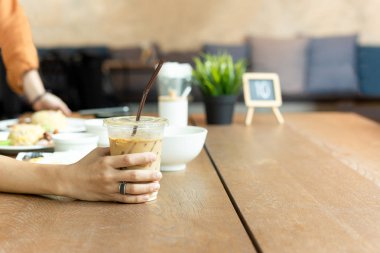 Bardak buzlu latte kahve gıda ile masaya öğle anda tutmakta..