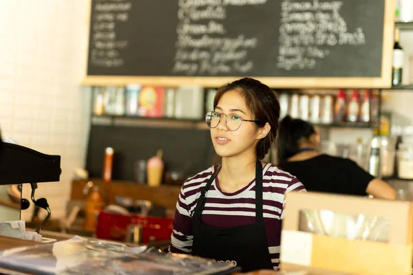 Azjatyckie dziewczyny z okulary kelnerka w kawiarni na sobie fartuch stojący. — Zdjęcie stockowe