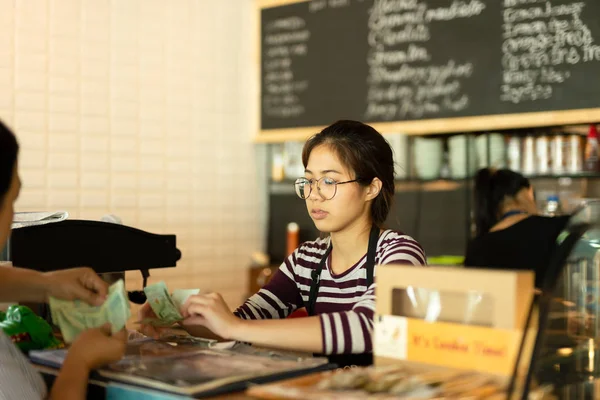 Młody barista, biorąc pieniądze od klienta wynagrodzenia za napoje w coffee shop. — Zdjęcie stockowe