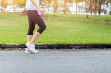 Yumuşak odak kadın parkta şişe su ile yaz aylarında yürüyüş.