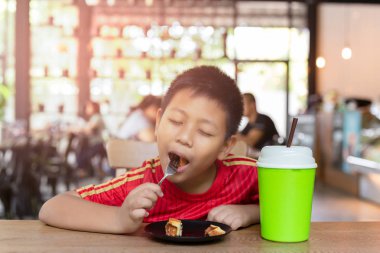 Mutlu yüz Asya oğlan zevk yeme çikolata waffle içinde Restoran.