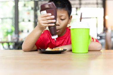 Mutlu yüz Asya çocuk sıkma çikolata üzerinde waffle için kahvaltı.