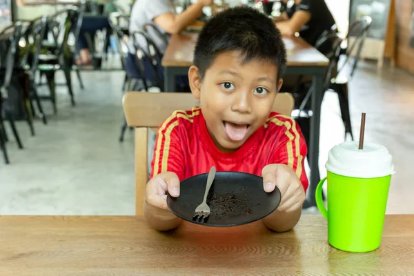 Мальчик пустое грязное блюдо за вафлей с шоколадным соусом на столе . — стоковое фото