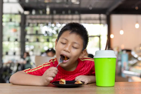 Mutlu yüz Asya oğlan zevk yeme çikolata waffle içinde Restoran.