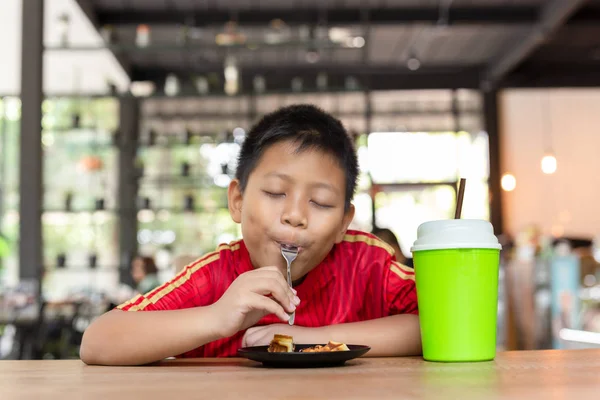 Veselý obličej asijský chlapec Vychutnejte si čokoládovou vafle v restauraci. — Stock fotografie