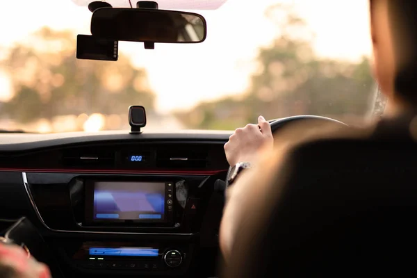 Handen op stuurwiel rijden bij zonsondergang. — Stockfoto