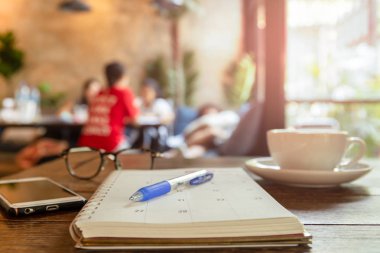 Kahve ve hücre fincan ile takvim kitabında seçilen odak kalem 