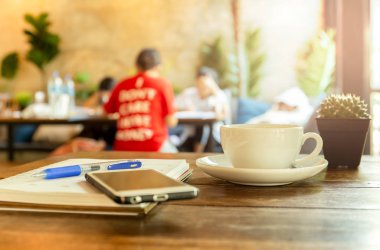 Masa üzerinde cep telefonu ve kitap, kalem ile kahve fincan.