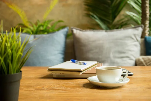 Kopp kaffe med böcker och penna på trä bord i kafé. — Stockfoto