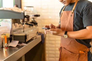 Barista kahve dükkanında cep telefonu kontrol.