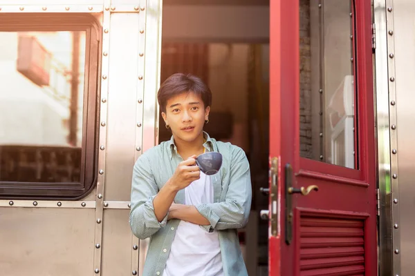 Retrato de la mano asiática hombre sosteniendo taza de café relajante en la puerta principal . — Foto de Stock