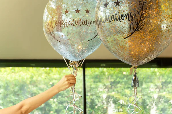 Hand hält Luftballons mit Glückwunschtext darauf bei der Party-Dekoration. — Stockfoto