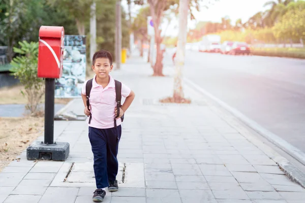 Asiático escuela chico en uniforme con mochila caminar de vuelta a casa . —  Fotos de Stock