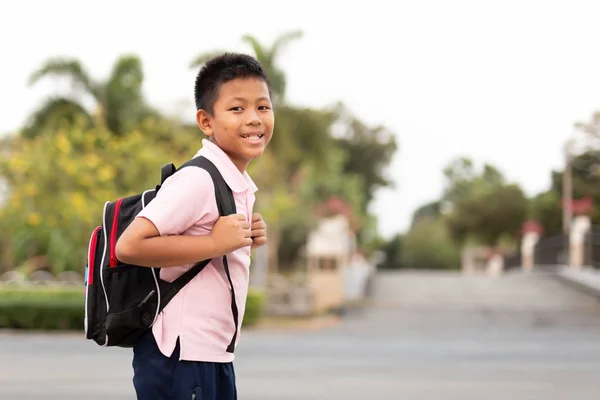 Happy Asian School Boy i uniform med ryggsäck går hem. — Stockfoto