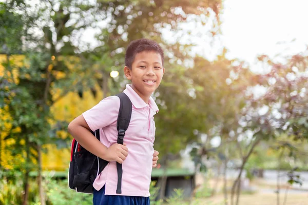 Happy asian school boy in uniform with backpack walking back home.
