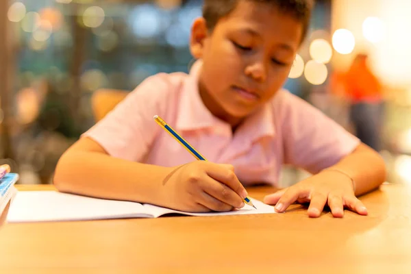 Asiático escolar mano con lápiz haciendo su tarea en casa . —  Fotos de Stock