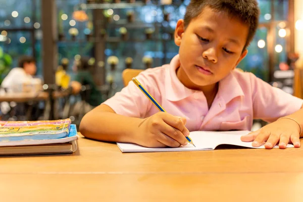 Asiático escolar mano con lápiz haciendo su tarea en casa . —  Fotos de Stock