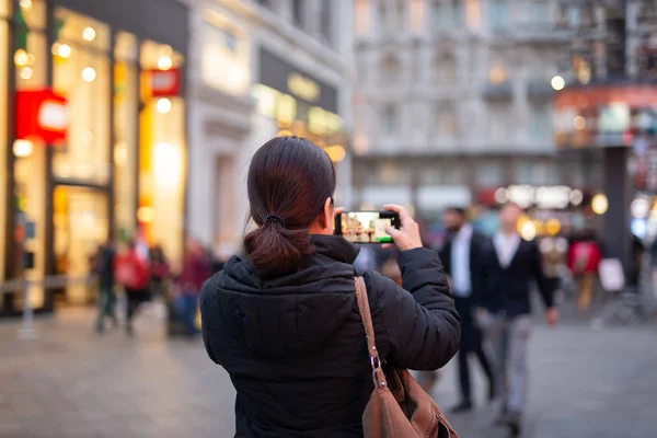 Kobieta turysta robi zdjęcia miasta z telefonu komórkowego w rozmytym tle. — Zdjęcie stockowe