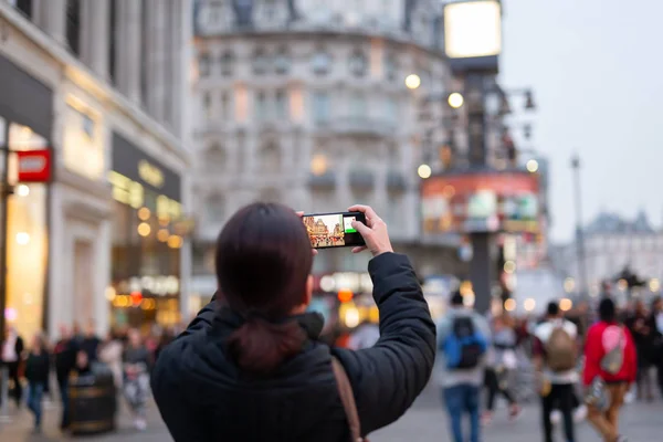 Kobieta turysta robi zdjęcia miasta z telefonu komórkowego w rozmytym tle. — Zdjęcie stockowe