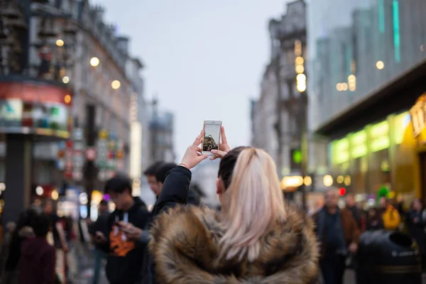 Kobieta turysta robi zdjęcia miasta z telefonu komórkowego na ulicy w rozmazanym tle. — Zdjęcie stockowe