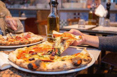 Restoranda tabaktan lezzetli pizza dilimleri alan kadın el.