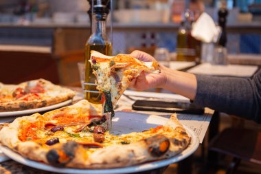 Restoranda tabaktan lezzetli pizza dilimleri alan kadın el.