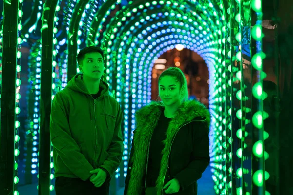 Retrato de mestiço adolescente irmão e irmã de pé em luz de néon verde . — Fotografia de Stock