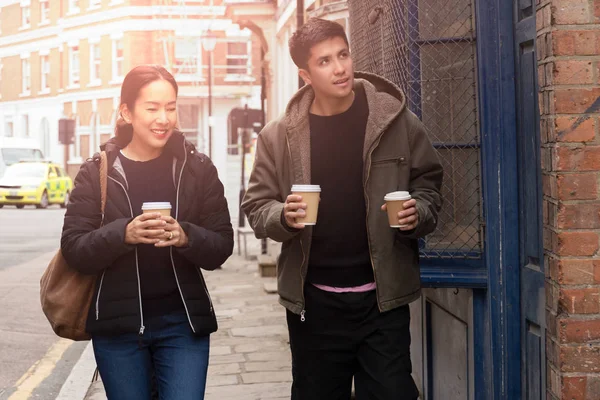 Счастливая мать с сыном ходит по улице с кофе на вынос в руках . — стоковое фото