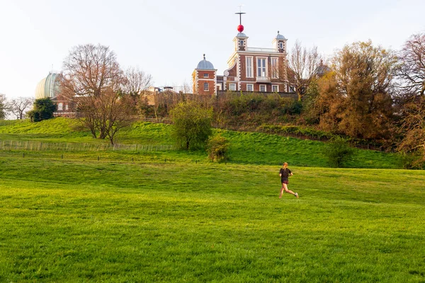 Mulher jogging no parque com Greenwich tempo médio no fundo . — Fotografia de Stock