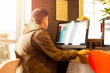 Genç bir öğrenci kütüphanede bilgisayar üzerinde çalışıyor..