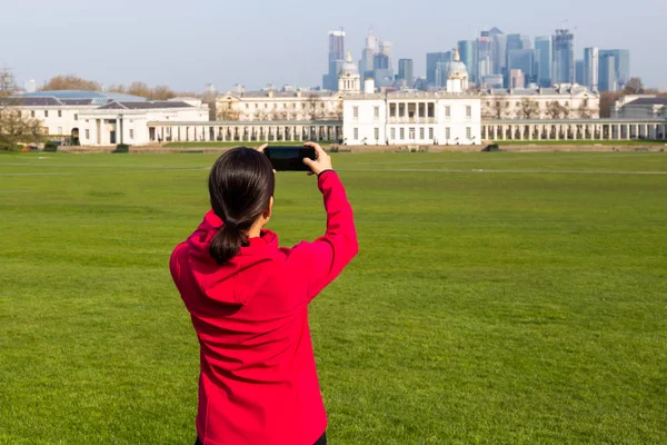Kobieta turysta robi zdjęcia budynku w parku z telefonu komórkowego. — Zdjęcie stockowe