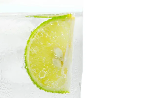 Nahaufnahme Scheibe Kalk in Glas Spritzwasser isoliert. — Stockfoto