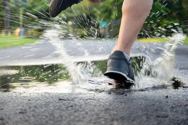 Homem exercício correndo através de poça salpicando seus sapatos . — Fotografia de Stock