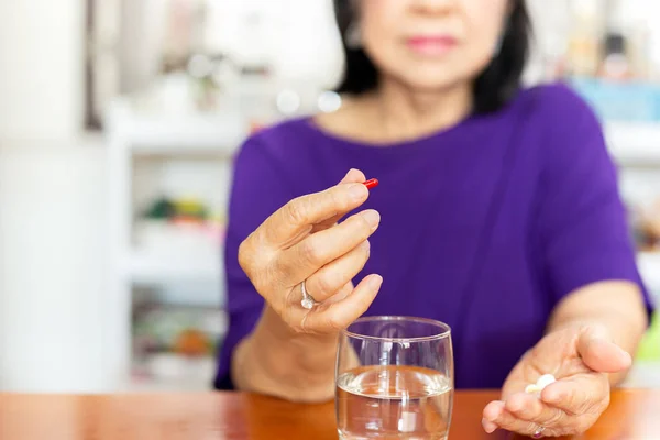 Senior Kvinna händer håller tabletten med glas vatten på bordet. — Stockfoto