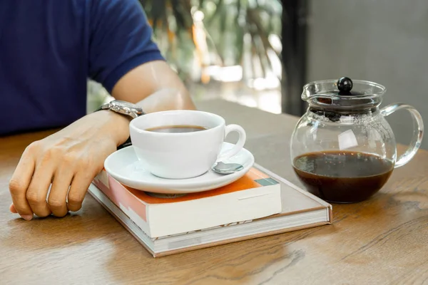 Man sits on table with coffee on the book in coffee shop. — Stock Photo, Image