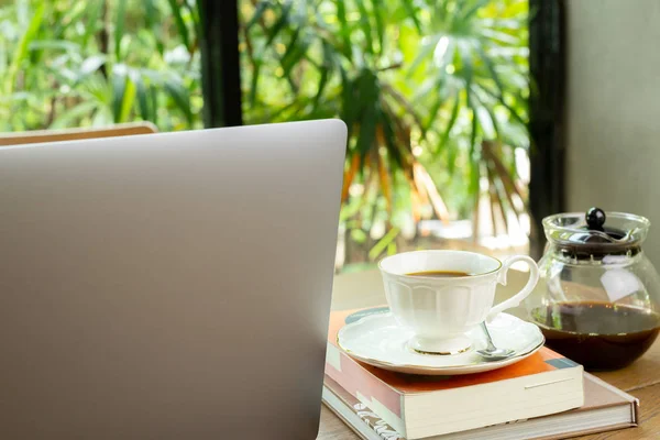 Bärbar dator och kopp kaffe med bok på träbord i Café. — Stockfoto