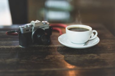 Sabah ahşap masada kamera ve kahve fincanı.
