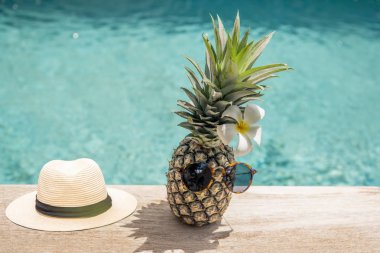 Yüzme Havuzu yakın Plumeria çiçek ve şapka ile güneş gözlüğü komik ananas.