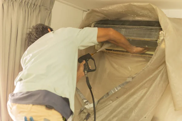 Arbeiter reinigen Wandklimaanlage mit Hochdruck-Wasserstrahlpumpe zu Hause. — Stockfoto