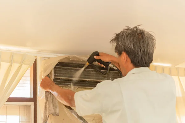 Travailleur nettoyage mur climatiseur avec pompe à jet d'eau haute pression à la maison . — Photo