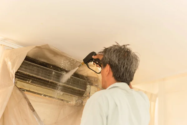 Werknemer schoonmaken muur airconditioner met hoge druk water jet pomp thuis. — Stockfoto