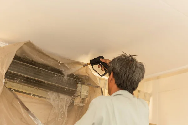 Werknemer schoonmaken muur airconditioner met hoge druk water jet pomp thuis. — Stockfoto