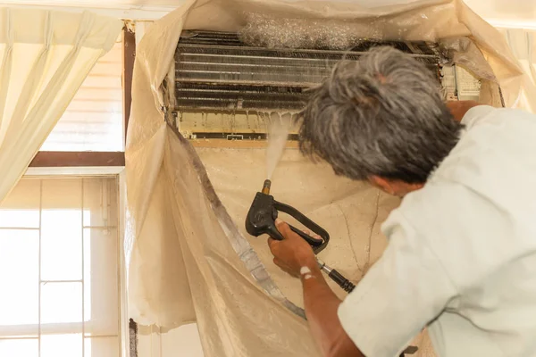 Arbeiter reinigen Wandklimaanlage mit Hochdruck-Wasserstrahlpumpe zu Hause. — Stockfoto