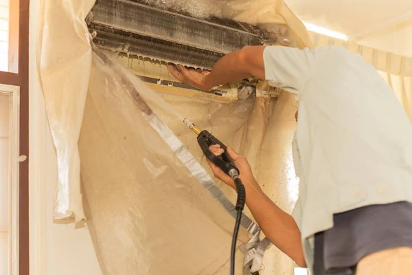 Werknemer schoonmaken muur airconditioner met hoge druk water jet pomp thuis. — Stockfoto