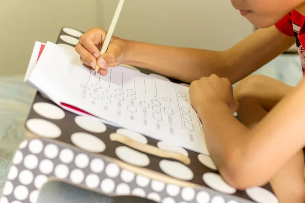 Joven asiático chico haciendo su homeworks en un cama . —  Fotos de Stock