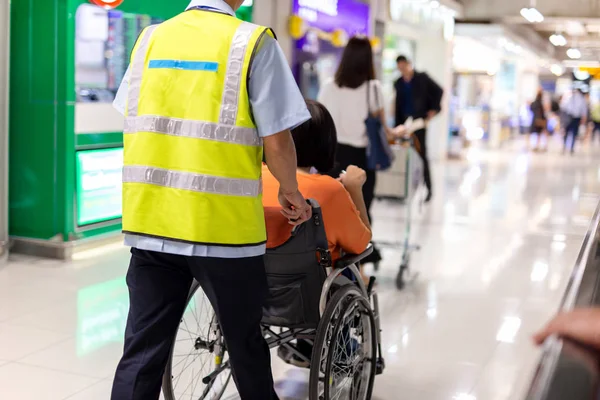 Caretaker push elderly woman on  wheelchair in airport terminal.