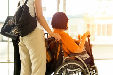 Tekerlekli sandalyede annesi olan kadın Uluslararası havaalanında biniş bekliyor.