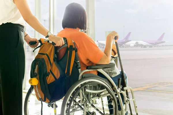 Tekerlekli sandalyede annesi olan kadın Uluslararası havaalanında biniş bekliyor.