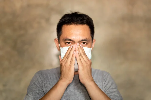 Asian mężczyzna ubrany w maskę na twarz z zakrytą ręką usta podczas kaszlu. — Zdjęcie stockowe
