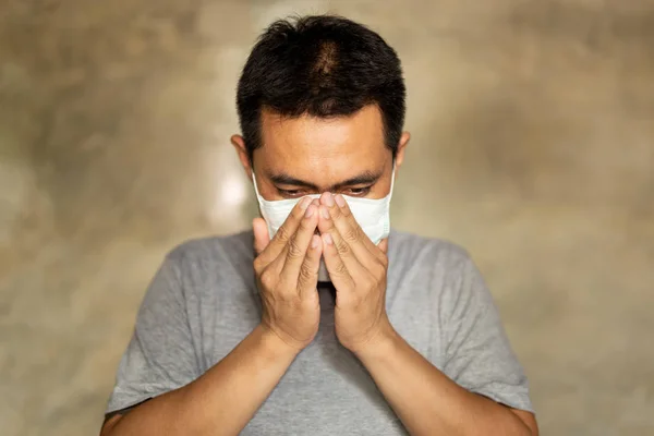Asian mężczyzna ubrany w maskę na twarz z zakrytą ręką usta podczas kaszlu. — Zdjęcie stockowe